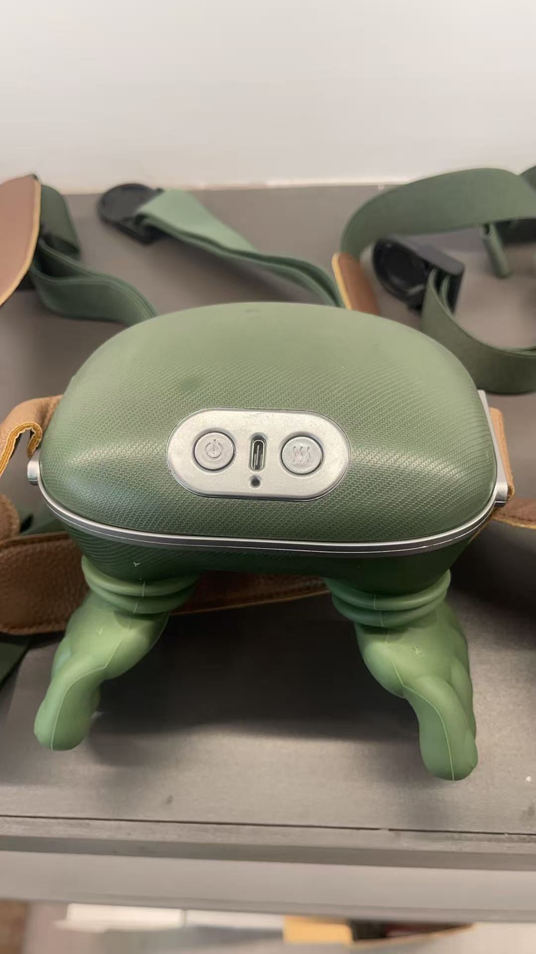 Green neck massager with straps on a metallic surface