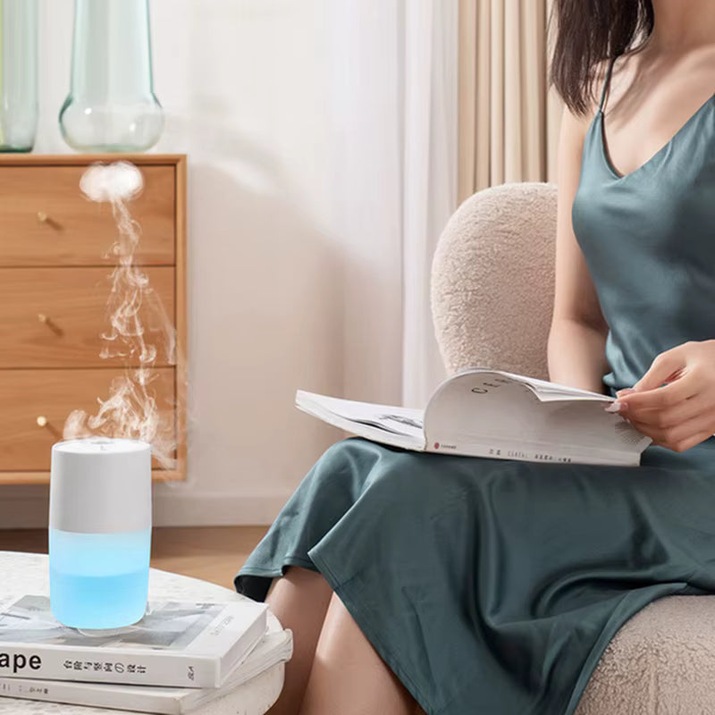 Woman reading a book next to a diffuser emitting steam in a cozy room.