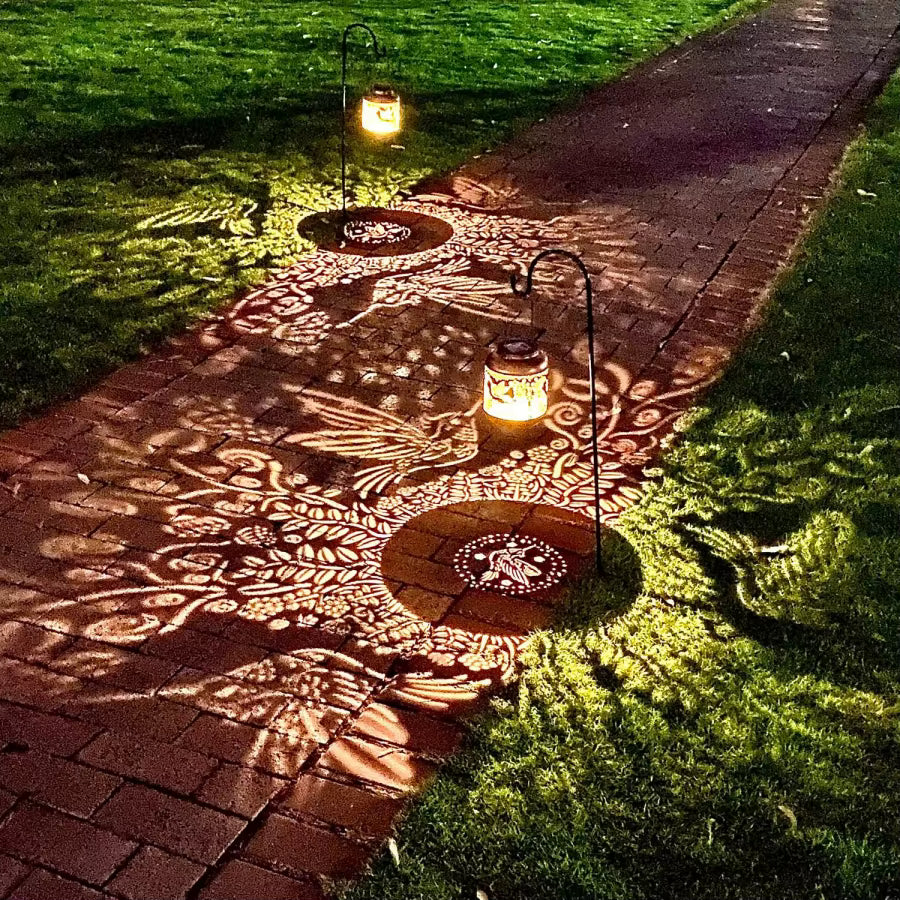 Decorative garden path with illuminated lanterns casting intricate patterns on the ground.