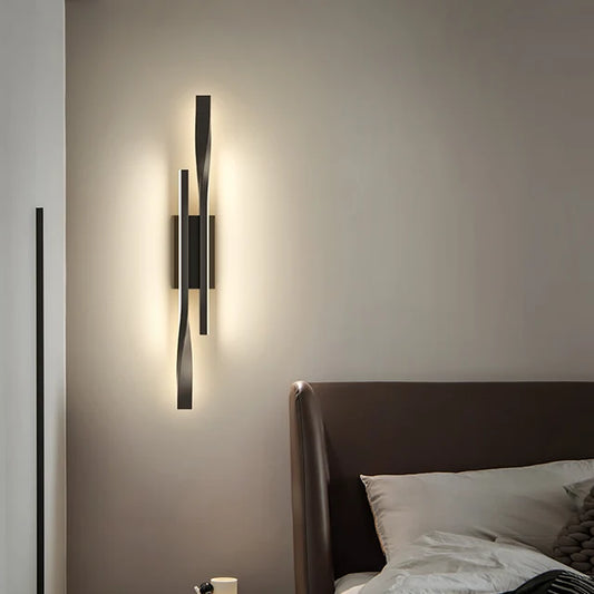 Modern wall sconce on a bedroom wall with a bed in the foreground